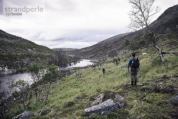 Fliegenfischer beim Wandern am Flussufer mit Bergen  Lakselv  Norwegen