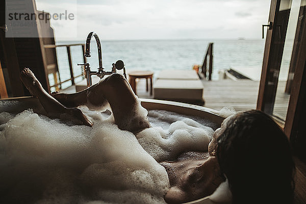 Frau entspannt sich in Badewanne mit Blick auf das Meer  Insel Maguhdhuvaa  Gaafu-Dhaalu-Atoll  Malediven