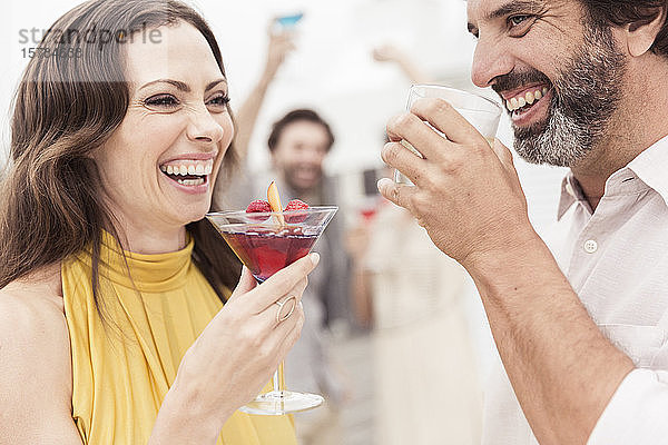 Glückliches Paar und Freunde beim geselligen Beisammensein auf einer Cocktailparty