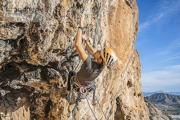 Frau klettert an Felswand