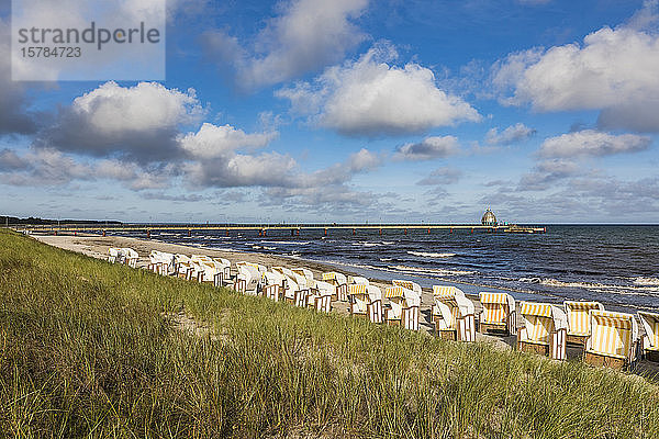 Deutschland  Mecklenburg-Vorpommern  Reihen von Strandkorbstühlen am sandigen Küstenstrand im Sommer mit Pier im Hintergrund