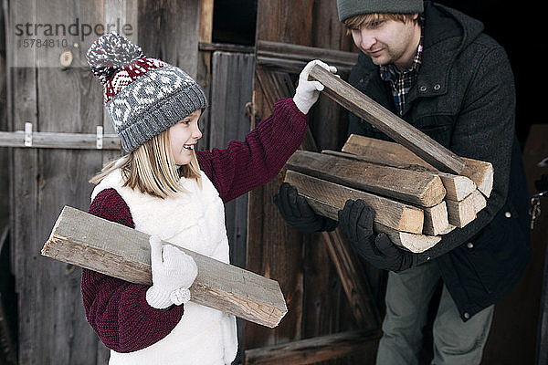Tochter gibt ihrem Vater im Winter Brennholz