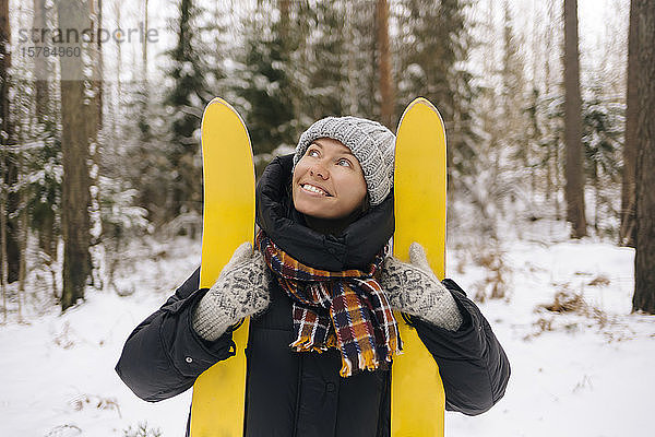 Porträt einer lächelnden Frau mit Skiern im Winterwald