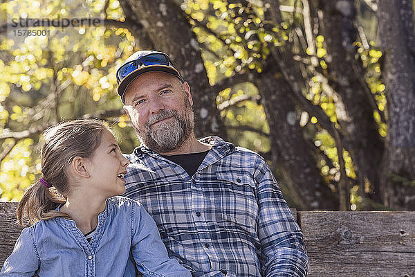 Vater und Tochter wandern in den Bergen  machen eine Pause  sitzen auf einer Bank