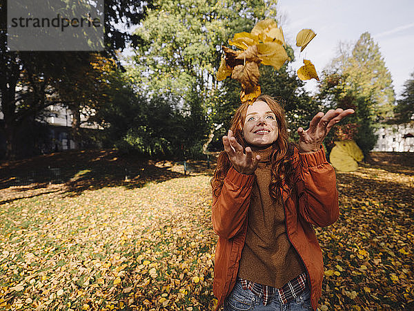 Glückliche rothaarige Frau genießt den Herbst in einem Park
