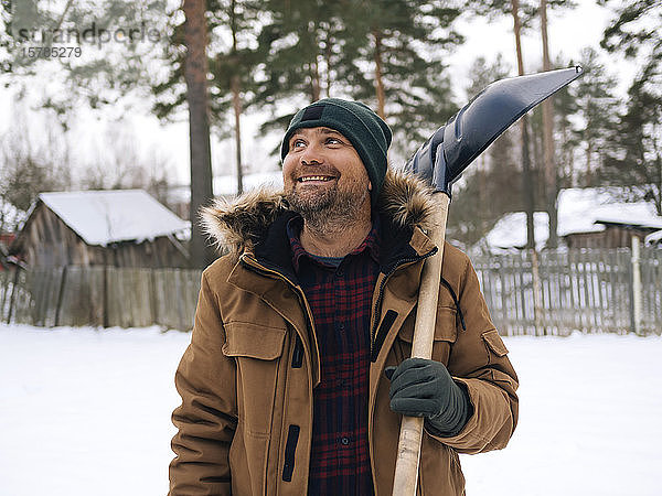 Porträt eines lächelnden Mannes mit Schneeschaufel  der nach oben schaut