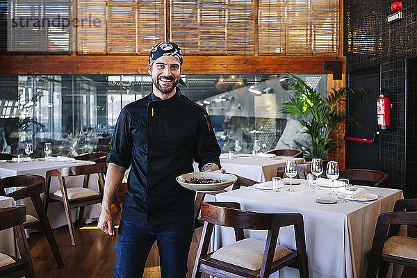 Porträt eines lächelnden Mannes  der im Restaurant ein Gericht serviert