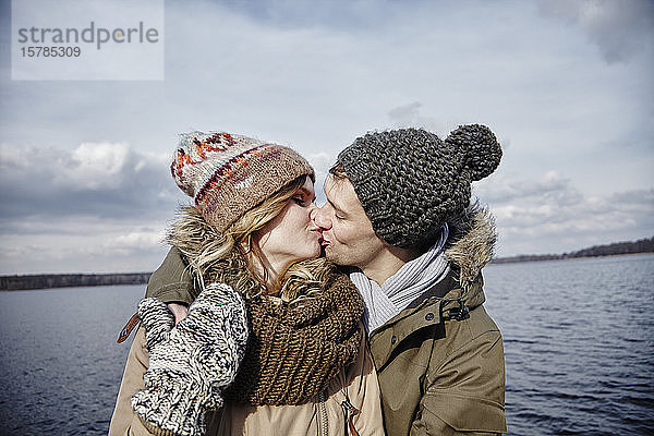 Junges Paar küsst sich vor einem See