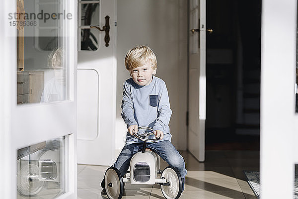 Porträt eines Jungen  der zu Hause mit einem Spielzeugauto spielt