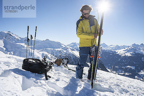 Mann im Gegenlicht bei der Vorbereitung von Skiern für eine Skitour  Graubünden  Schweiz