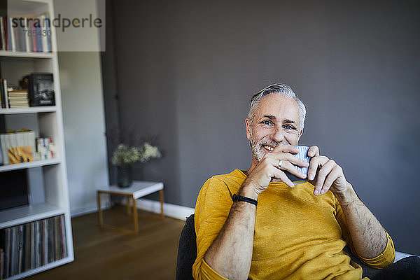 Porträt eines lächelnden entspannten reifen Mannes zu Hause bei einer Tasse Kaffee