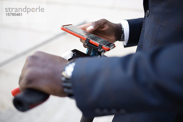 Schnittansicht eines Mannes mit einem Roller  der ein Smartphone benutzt