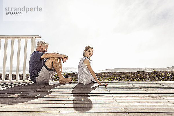 Vater und Tochter sitzen bei Sonnenschein auf der Terrasse