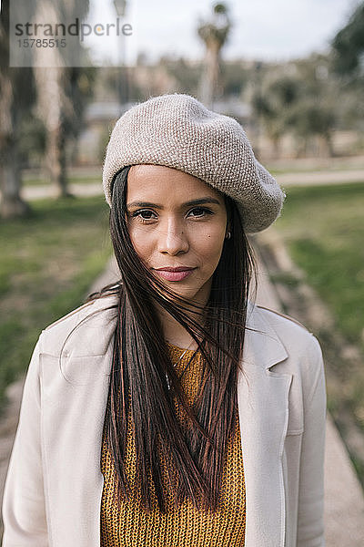 Porträt einer jungen Frau mit Baskenmütze in einem Park