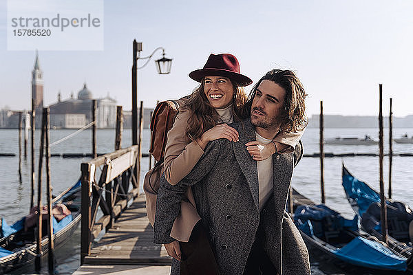 Junger Mann nimmt seine Freundin am Hafen von Venedig  Italien  huckepack