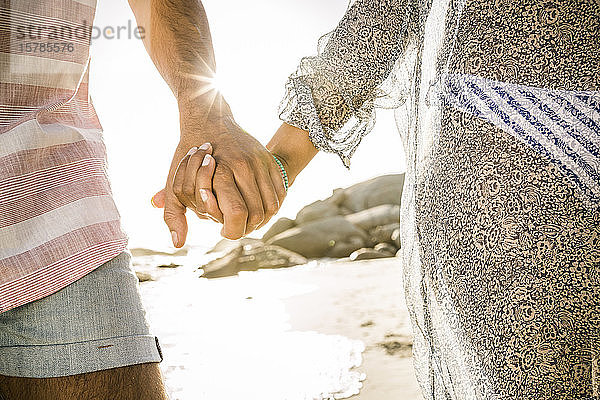Nahaufnahme eines Paares  das sich am Strand an den Händen hält