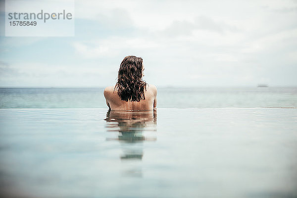 Rückansicht einer Frau  die sich im Infinity-Pool entspannt  Insel Maguhdhuvaa  Gaafu-Dhaalu-Atoll  Malediven