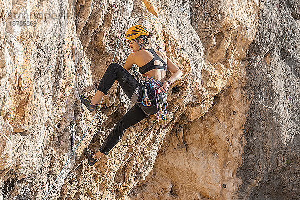 Frau klettert an Felswand