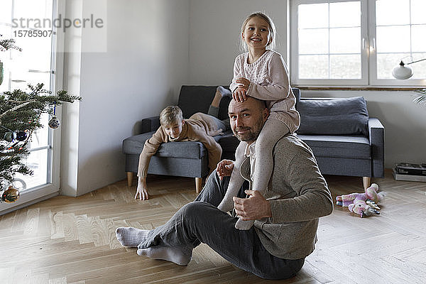 Porträt eines reifen Mannes  der zu Hause auf dem Boden sitzt und mit seiner kleinen Tochter spielt