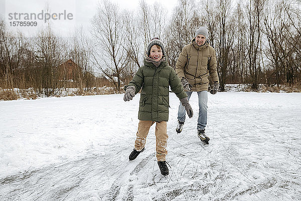 Glücklicher Junge läuft zusammen mit Vater auf dem Eis