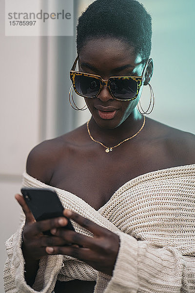 Porträt einer jungen Frau mit Sonnenbrille und Smartphone