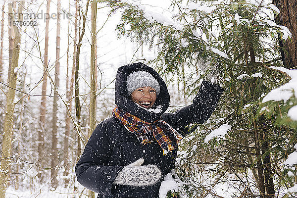 Porträt einer lachenden Frau im Winterwald bei Schneefall