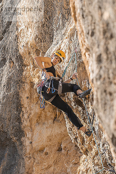 Frau klettert an Felswand