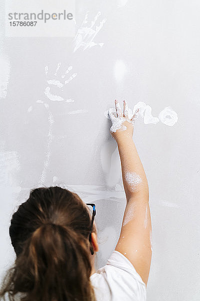Mädchen malt mit dem Finger an einer Wand
