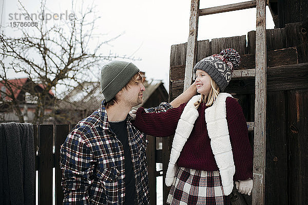 Glücklicher Vater mit Tochter an einer Holzleiter im Winter