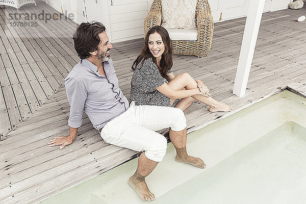 Glückliches Paar beim Entspannen am Pool eines Ferienhauses