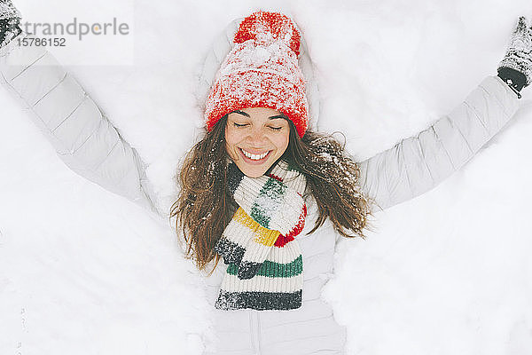 Porträt einer glücklichen Frau auf Schnee liegend