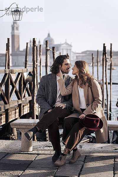 Junges Paar sitzt am Wasser in Venedig  Italien