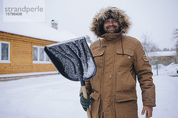 Porträt eines lächelnden Mannes mit Schneeschaufel