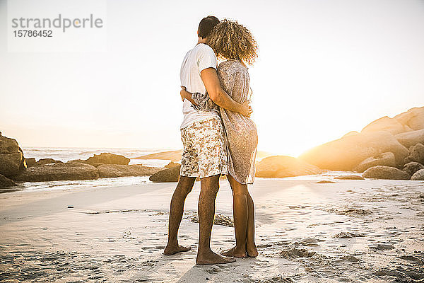 Paare umarmen sich am Strand und genießen den Sonnenuntergang