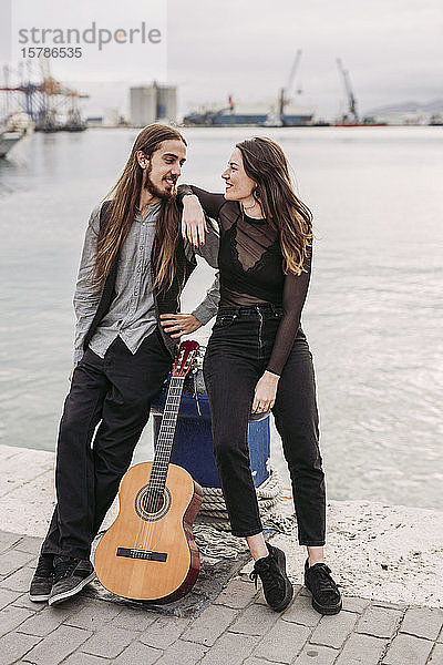 Junges Paar mit einer Gitarre am Hafen