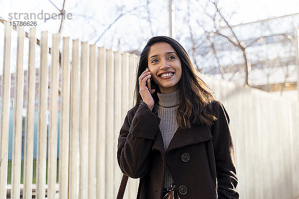 Lächelnde junge Frau am Telefon in der Stadt