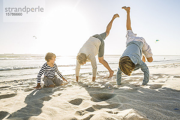 Verspielter Vater mit zwei Söhnen  die sich am Strand amüsieren