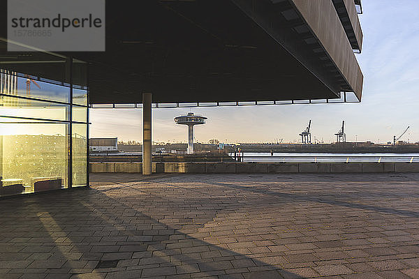 Deutschland  Hamburg  Vordach über dem Bürgersteig in der HafenCity bei Sonnenaufgang mit Leuchtturm Null im Hintergrund