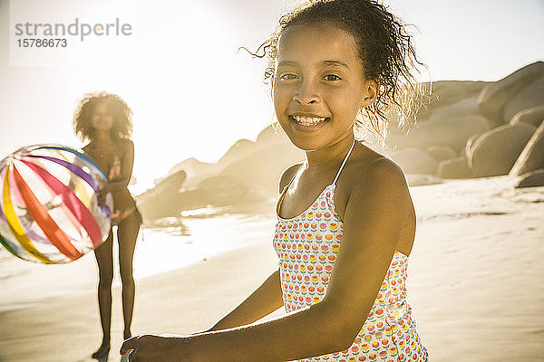 Porträt eines glücklichen Mädchens  das mit seiner Mutter am Strand spielt