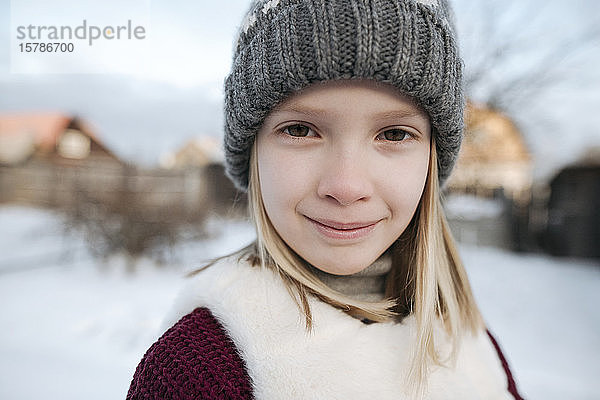 Porträt eines lächelnden Mädchens mit Wollmütze im Winter