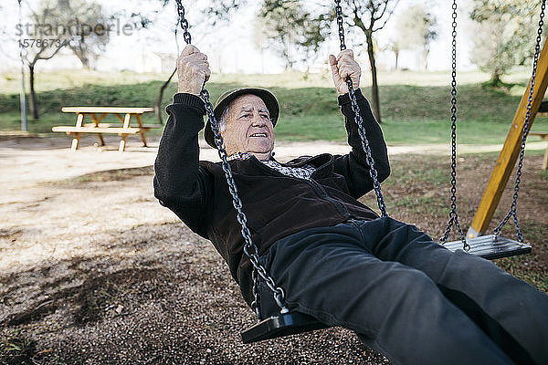 Alter Mann schaukelt auf Spielplatz im Park