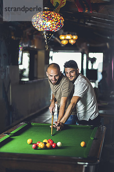 Schwules Paar spielt zusammen Billard in einer Bar