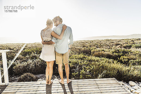 Zärtliches junges Paar umarmt sich im Sommer auf einer Terrasse an der Küste