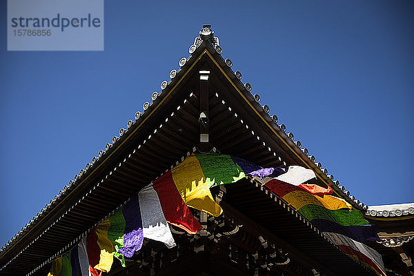 Japan  Präfektur Kyoto  Kyoto  Bunte Gebetsfahnen hängen vom Dach eines buddhistischen Tempels herunter