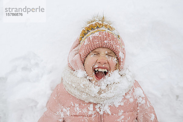 Porträt eines schreienden Mädchens auf Schnee liegend