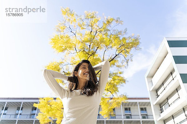 Glückliche junge Frau im Freien an einem Baum
