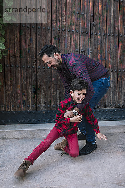 Glücklicher sorgloser Vater spielt mit seinem Sohn im Freien