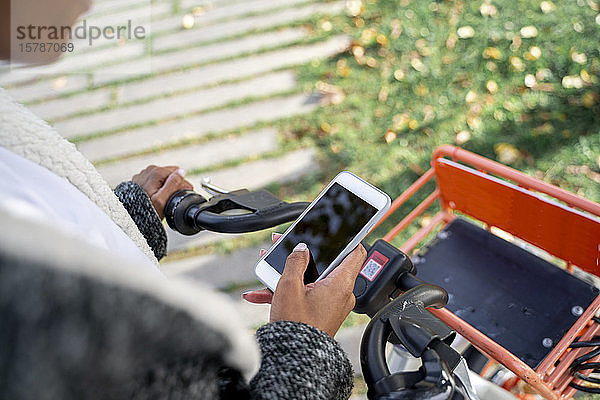 Geschäftsfrau nutzt Fahrradmitbenutzungssystem mit Smartphone