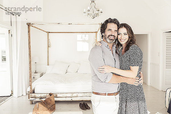 Glückliches Paar umarmt sich im Schlafzimmer eines Ferienhauses