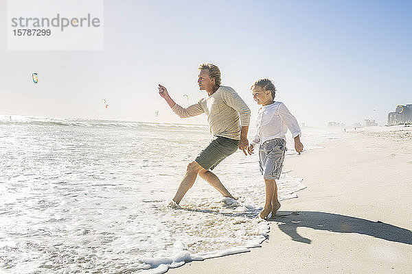 Vater amüsiert sich mit seinem Sohn am Strand und wirft Steine